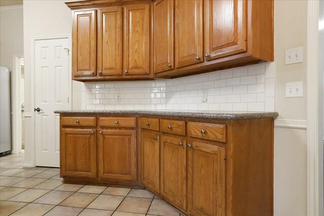 kitchen featuring light tile patterned flooring, stainless steel fridge, and backsplash