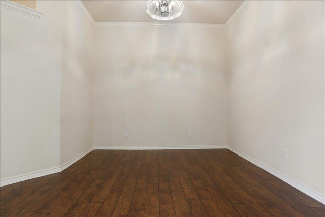 empty room with dark hardwood / wood-style flooring and crown molding