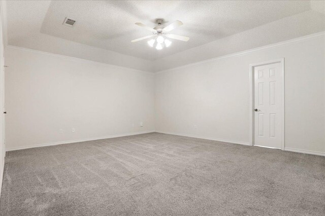 spare room with carpet, ceiling fan, a tray ceiling, crown molding, and a textured ceiling