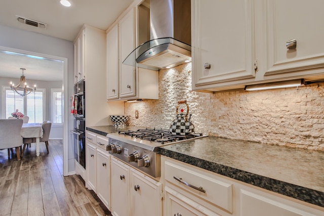 5419 87th St, Lubbock, TX 79424 - kitchen featuring wall chimney exhaust hood, dark countertops, black oven, a chandelier, and stainless steel gas cooktop