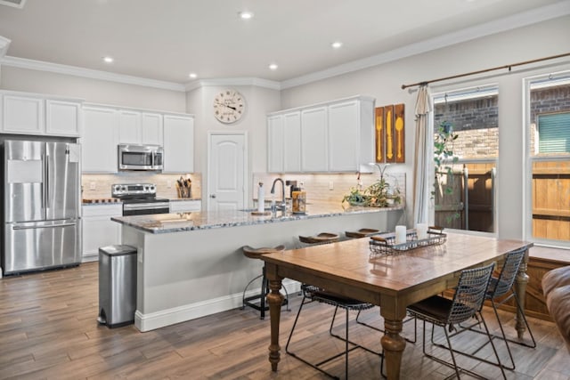 kitchen featuring stainless steel appliances, white cabinetry, light stone counters, and kitchen peninsula