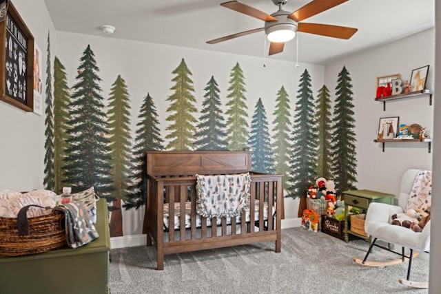 carpeted bedroom with a crib and ceiling fan