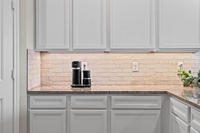 interior space featuring white cabinetry, stone countertops, and decorative backsplash