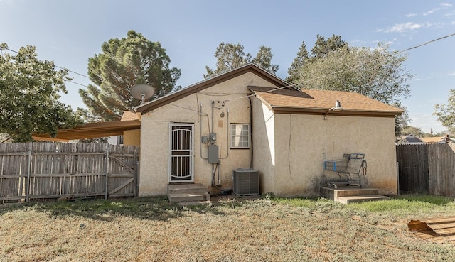 back of property featuring central AC and a lawn