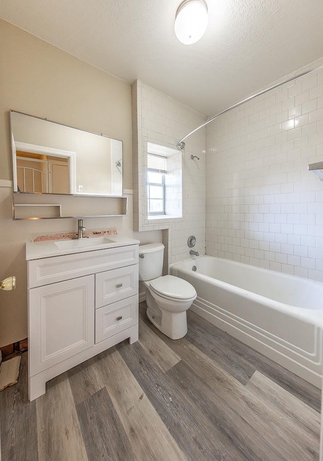 full bathroom featuring toilet, tiled shower / bath, a textured ceiling, vanity, and hardwood / wood-style floors