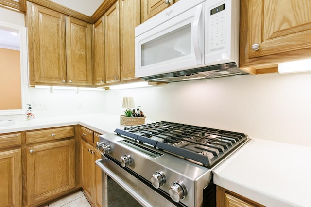 kitchen with light tile patterned floors and stainless steel gas range oven