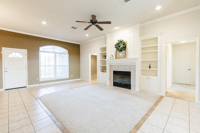 unfurnished living room with built in features, a fireplace, ornamental molding, light tile patterned floors, and ceiling fan