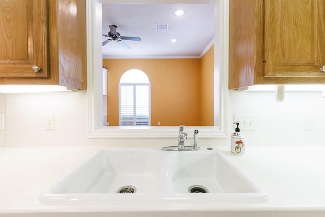 interior details with crown molding, sink, and ceiling fan