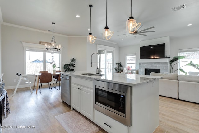 7008 17th St, Lubbock, TX 79416 - kitchen with appliances with stainless steel finishes, ceiling fan, light wood-style flooring, a fireplace, and ornamental molding