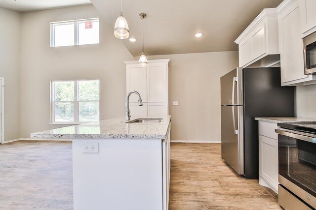 kitchen with sink, white cabinetry, light stone counters, stainless steel electric range oven, and hanging light fixtures