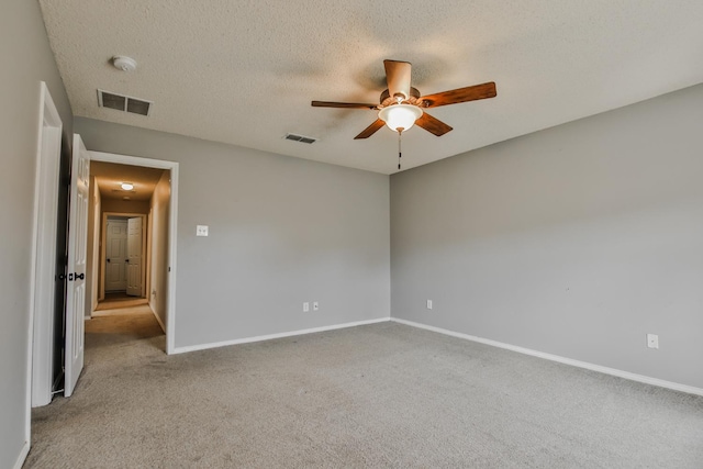 carpeted spare room featuring a textured ceiling and ceiling fan