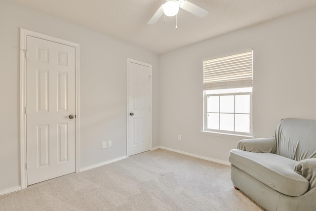 living area featuring light colored carpet and ceiling fan