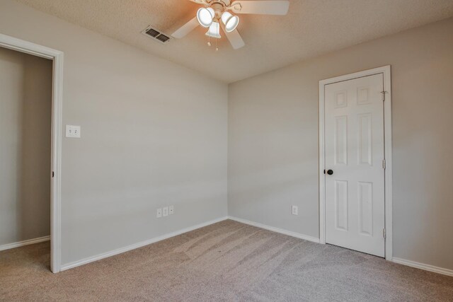 empty room with light carpet, a textured ceiling, and ceiling fan