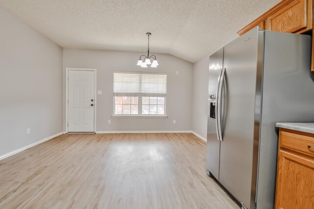 kitchen with vaulted ceiling, decorative light fixtures, a chandelier, stainless steel refrigerator with ice dispenser, and light hardwood / wood-style flooring