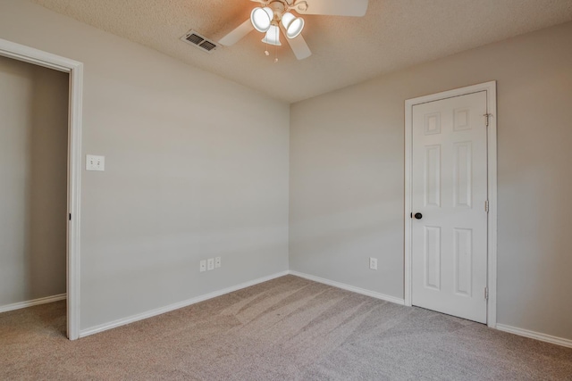 unfurnished room with a textured ceiling, light colored carpet, and ceiling fan