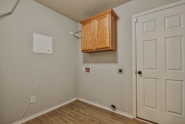 clothes washing area featuring hookup for a washing machine, cabinets, light hardwood / wood-style floors, a textured ceiling, and hookup for an electric dryer