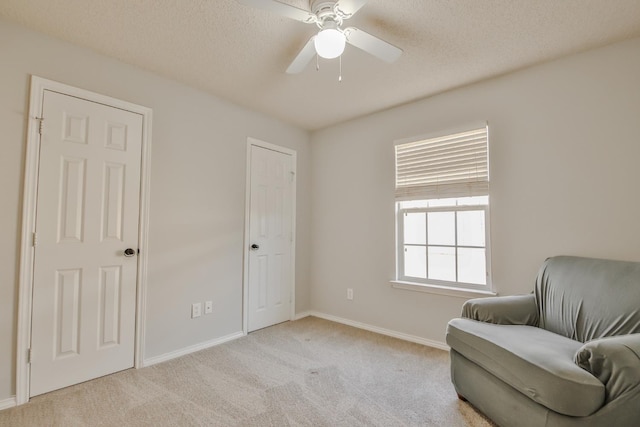 sitting room with ceiling fan, light carpet, and a textured ceiling