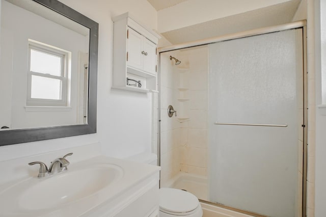 bathroom with a shower with door, vanity, and toilet