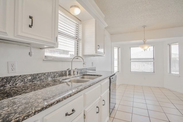 kitchen featuring dishwasher, sink, light tile patterned floors, and white cabinets