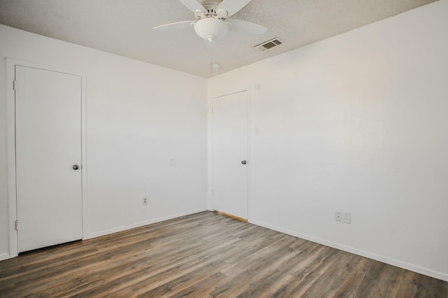 unfurnished room with a textured ceiling, dark hardwood / wood-style floors, and ceiling fan