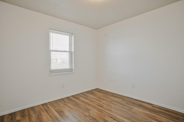 unfurnished room with wood-type flooring and a textured ceiling