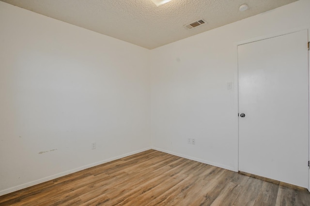 unfurnished room with hardwood / wood-style flooring and a textured ceiling