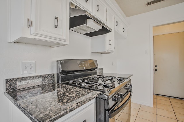 kitchen with black gas range oven, light tile patterned floors, white cabinetry, and dark stone countertops