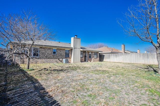 rear view of house featuring central AC and a lawn