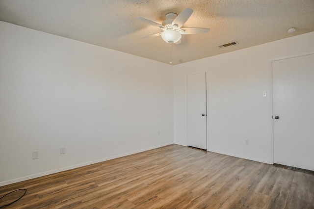 unfurnished room with ceiling fan, a textured ceiling, and light wood-type flooring