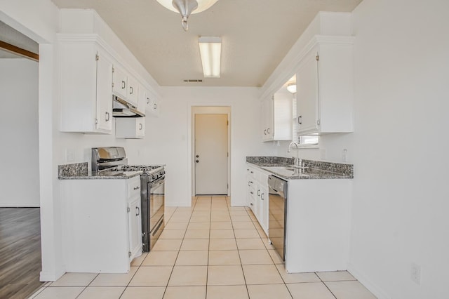 kitchen with white cabinetry, dark stone counters, light tile patterned floors, and black appliances