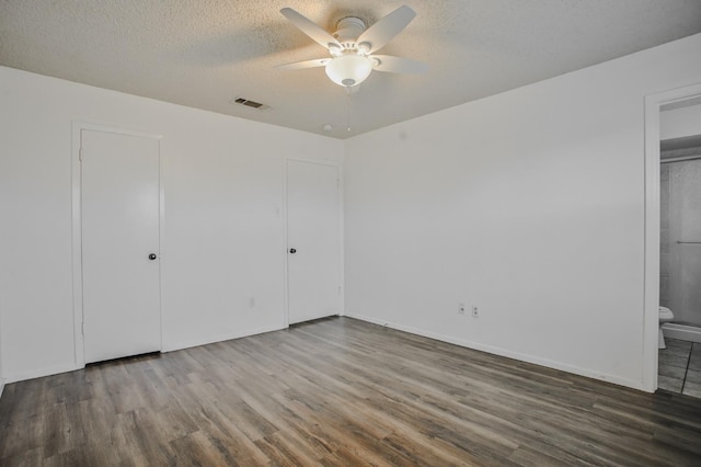 unfurnished bedroom with ceiling fan, connected bathroom, hardwood / wood-style floors, and a textured ceiling