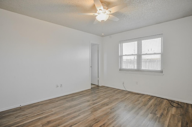 unfurnished room with ceiling fan, wood-type flooring, and a textured ceiling