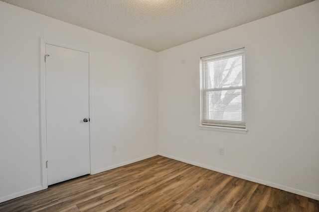 spare room with dark hardwood / wood-style floors and a textured ceiling