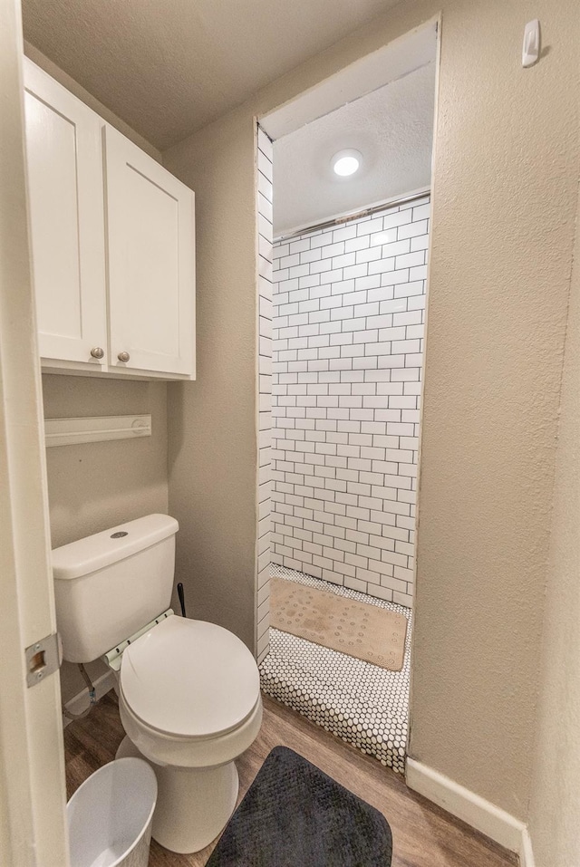 bathroom with wood-type flooring, toilet, and a shower