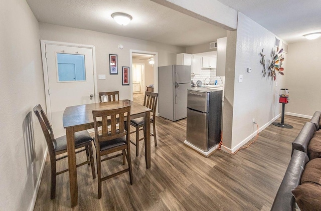 dining area with ceiling fan, dark hardwood / wood-style floors, sink, and a textured ceiling