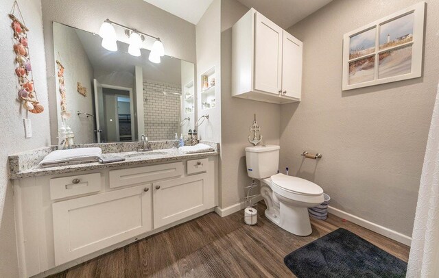 bathroom with hardwood / wood-style flooring, vanity, toilet, and walk in shower