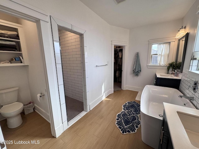 9906 Uvalde Ave, Lubbock, TX 79423 - bathroom with two vanities, tiled shower, wood finished floors, a spacious closet, and a tub to relax in
