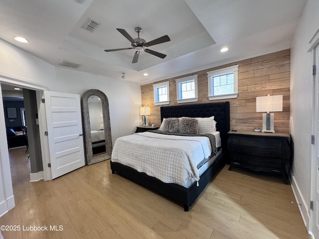 9906 Uvalde Ave, Lubbock, TX 79423 - bedroom featuring a raised ceiling, wood walls, light wood-style flooring, recessed lighting, and a ceiling fan