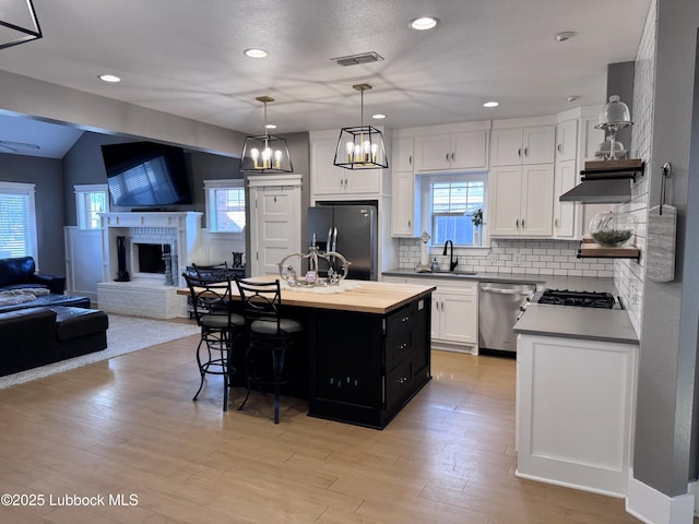 9906 Uvalde Ave, Lubbock, TX 79423 - kitchen with appliances with stainless steel finishes, open floor plan, a kitchen breakfast bar, white cabinetry, and backsplash