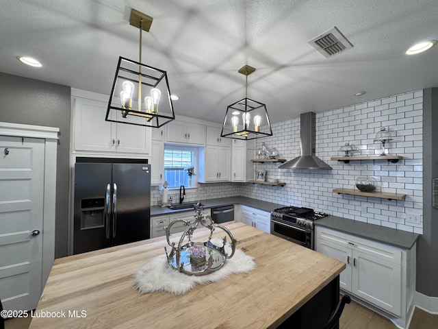 9906 Uvalde Ave, Lubbock, TX 79423 - kitchen featuring appliances with stainless steel finishes, wall chimney exhaust hood, open shelves, a chandelier, and decorative backsplash