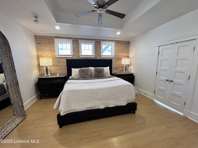 9906 Uvalde Ave, Lubbock, TX 79423 - bedroom with wood walls, a raised ceiling, recessed lighting, light wood-type flooring, and a ceiling fan