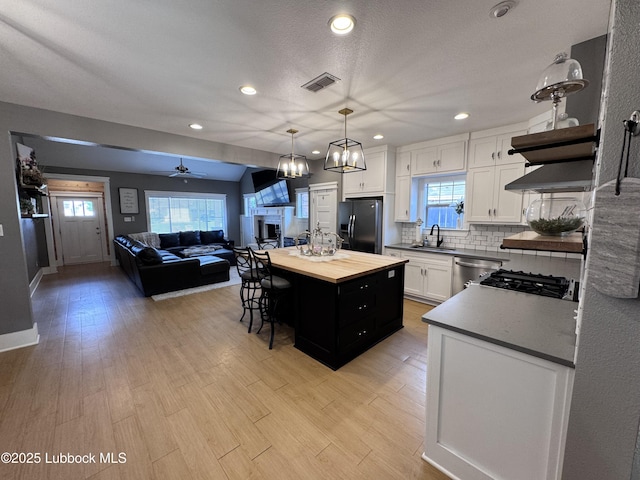 9906 Uvalde Ave, Lubbock, TX 79423 - kitchen featuring black fridge with ice dispenser, open shelves, butcher block counters, white cabinetry, and open floor plan