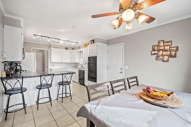 tiled dining room with ceiling fan, ornamental molding, sink, and a textured ceiling