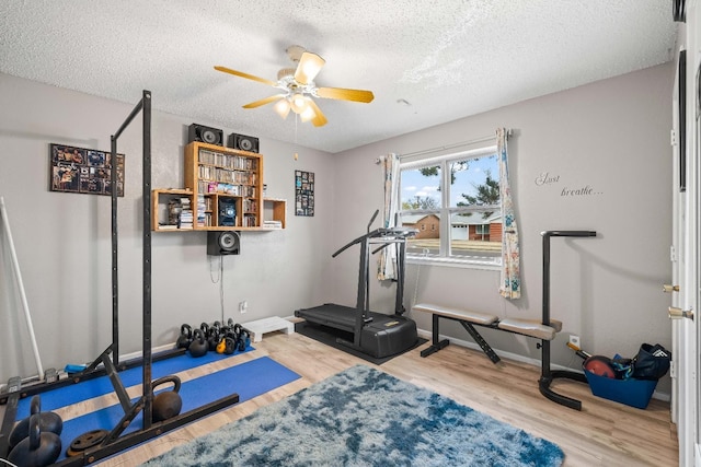 exercise room with hardwood / wood-style floors, a textured ceiling, and ceiling fan