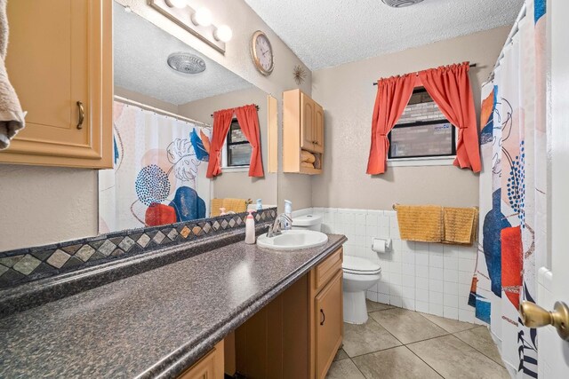 bathroom with tile walls, tile patterned flooring, vanity, a textured ceiling, and toilet