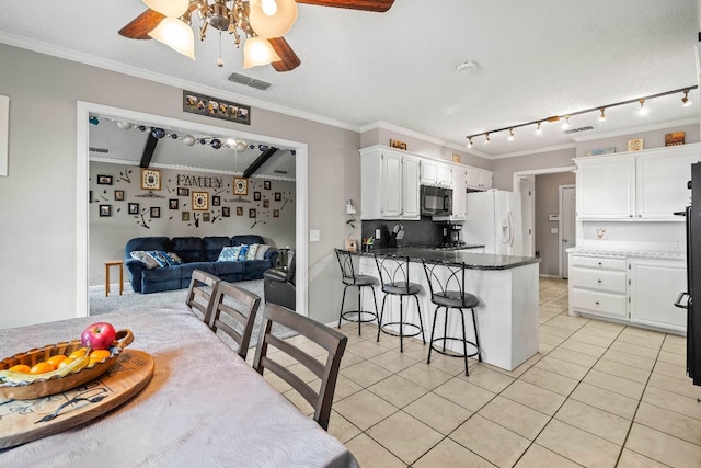 kitchen featuring light tile patterned flooring, a kitchen bar, white cabinetry, kitchen peninsula, and white refrigerator with ice dispenser