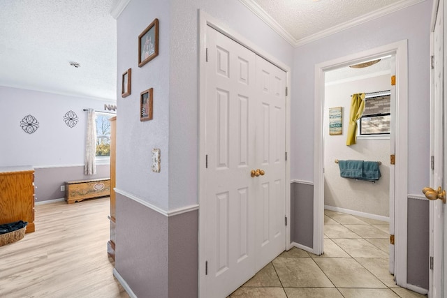 hall with crown molding, a textured ceiling, and light hardwood / wood-style flooring