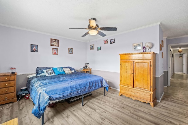 bedroom with ceiling fan, crown molding, light hardwood / wood-style floors, and a textured ceiling