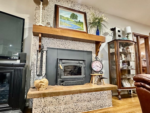 sitting room featuring a tile fireplace, wood-type flooring, and a wood stove