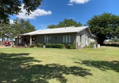 rear view of house featuring a porch and a yard